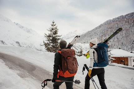 HOW TO SKITOUR © Alex Moling Zwei Skifahrer mit Rucksäcken und Skiern gehen einen schneebedeckten Bergweg hinauf