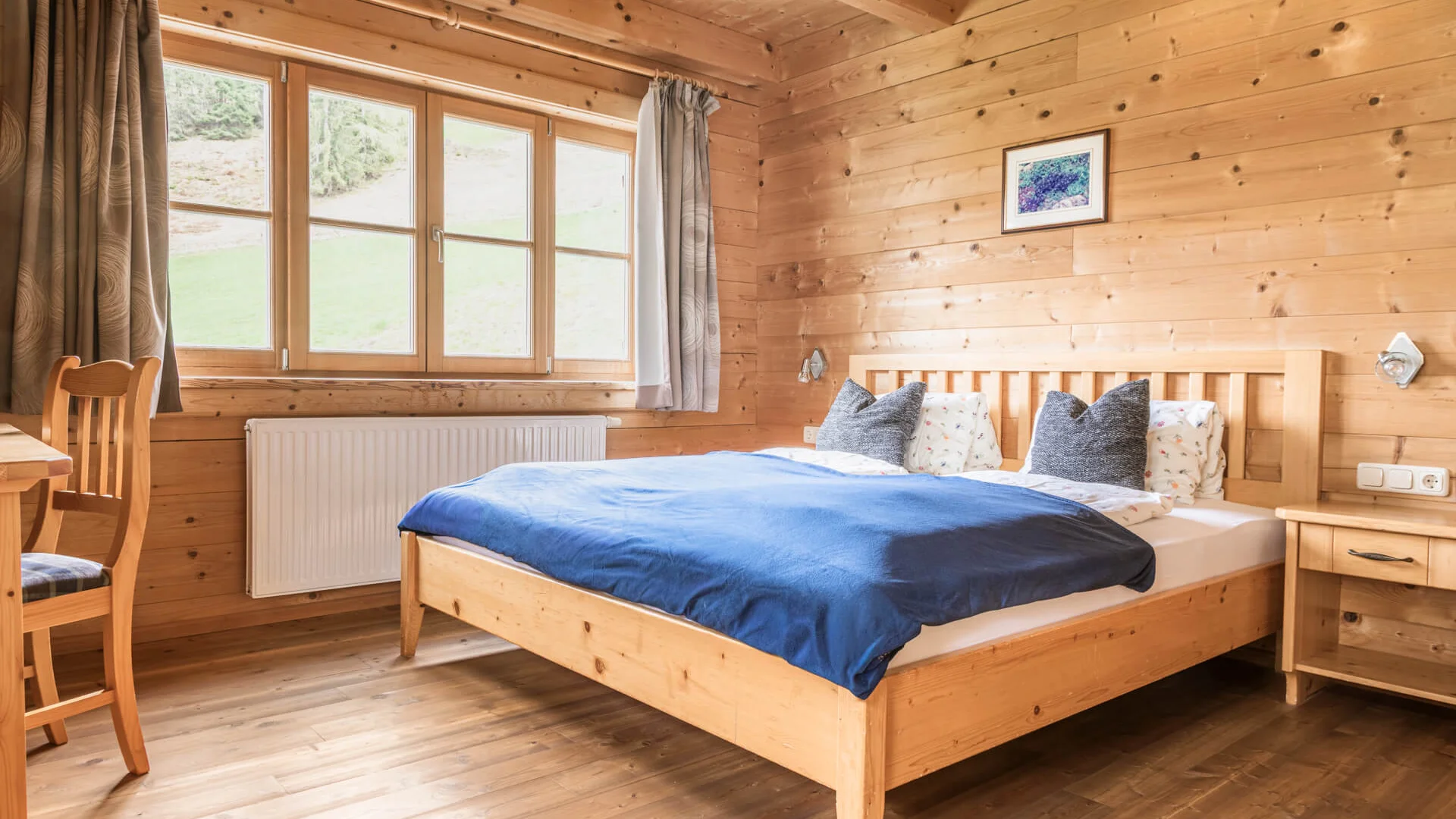 Bauerndörfl Rindereben © Bernd Suppan Bright bedroom with wooden walls and double bed with blue blanket