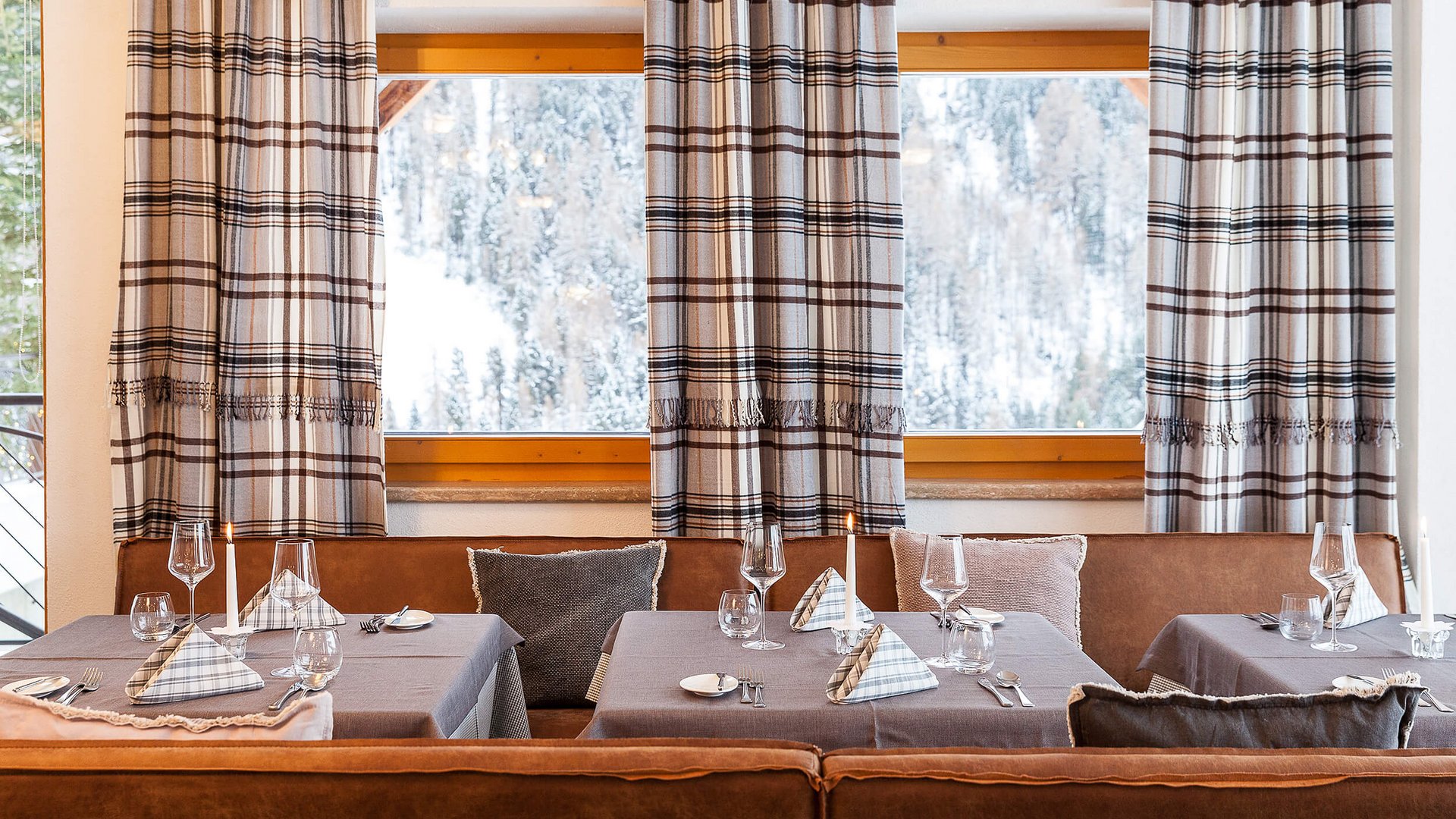 Gemütliches Restaurant mit eingedeckten Tischen und Schneelandschaftblick