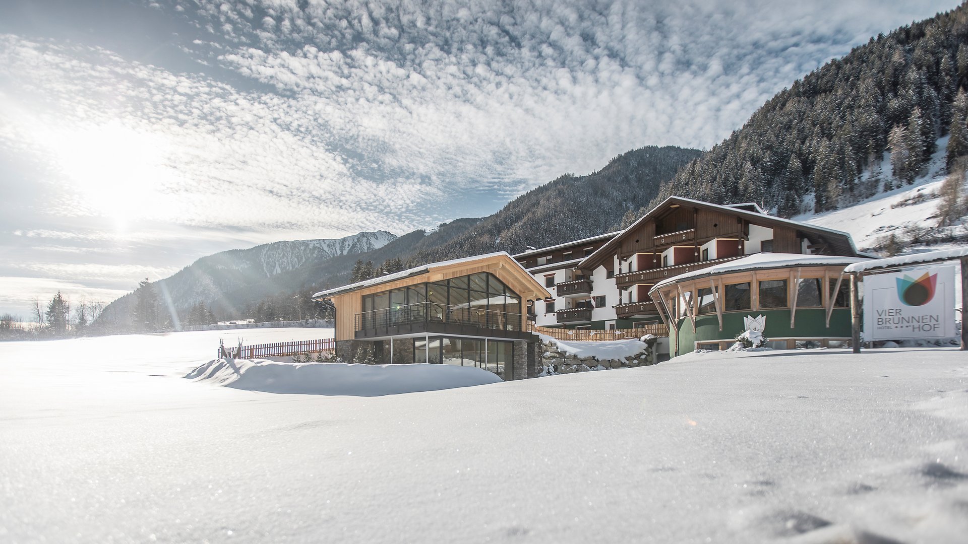 Hotel Vier Brunnenhof im verschneiten Tal vor bewaldetem Berg