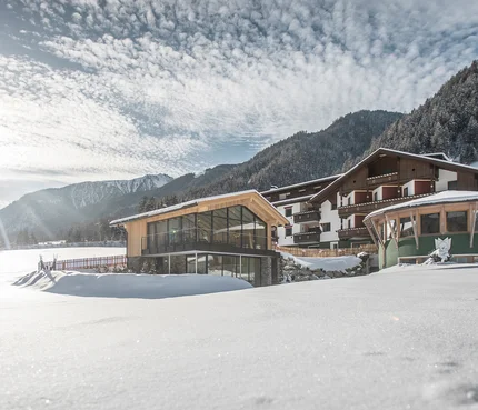 Hotel Vier Brunnenhof im verschneiten Tal vor bewaldetem Berg