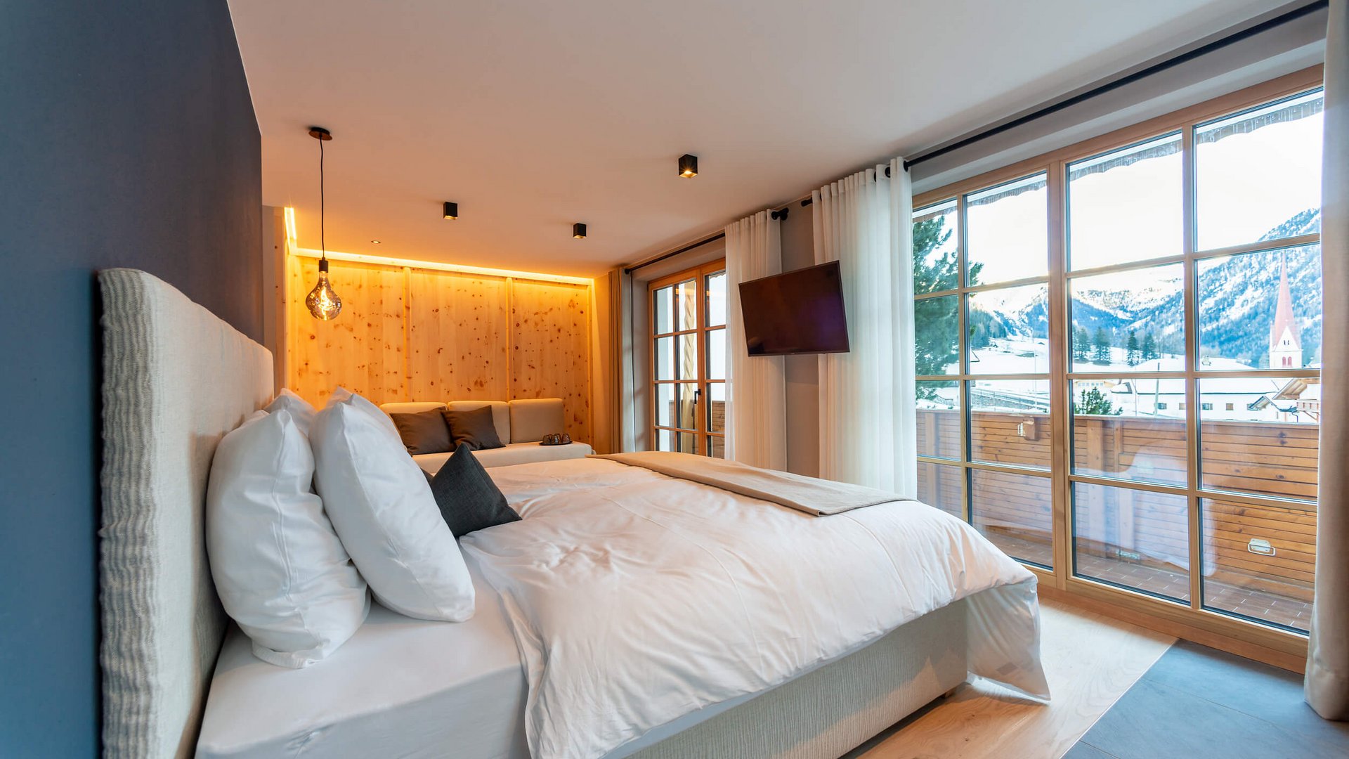 Modernes Schlafzimmer mit großem Bett und Bergblick durch Panoramafenster