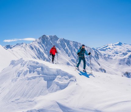 Two ski tourers hiking on snow-covered mountain on a sunny winter day