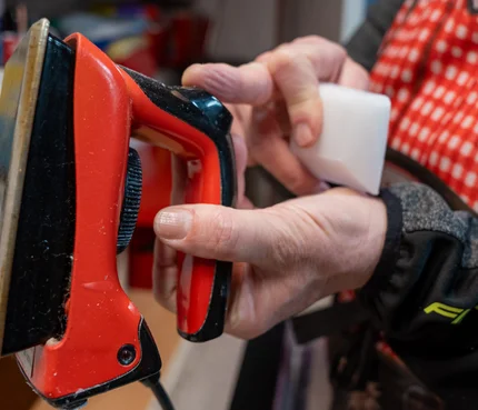 Person hält ein Rot- und Schwarze Bügeleisen und ein weißes Werkzeug in der Hand
