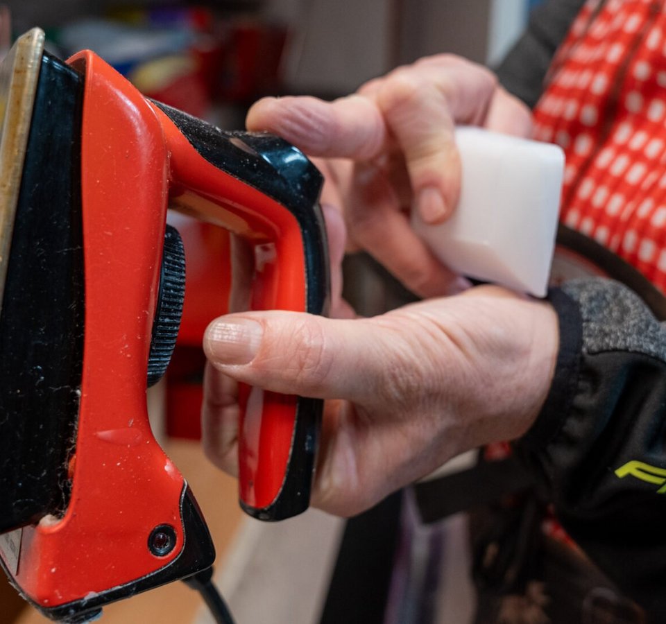 Person hält ein Rot- und Schwarze Bügeleisen und ein weißes Werkzeug in der Hand