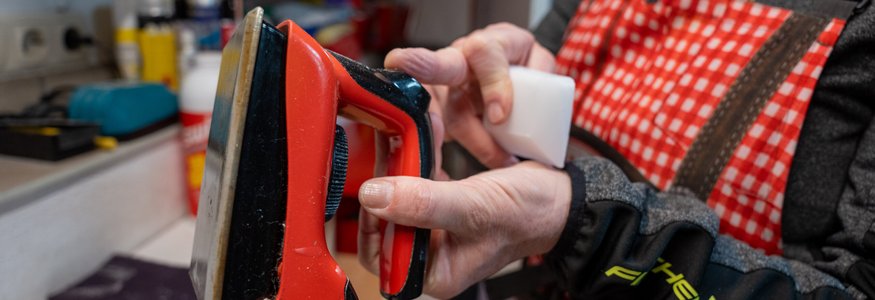 Person hält ein Rot- und Schwarze Bügeleisen und ein weißes Werkzeug in der Hand