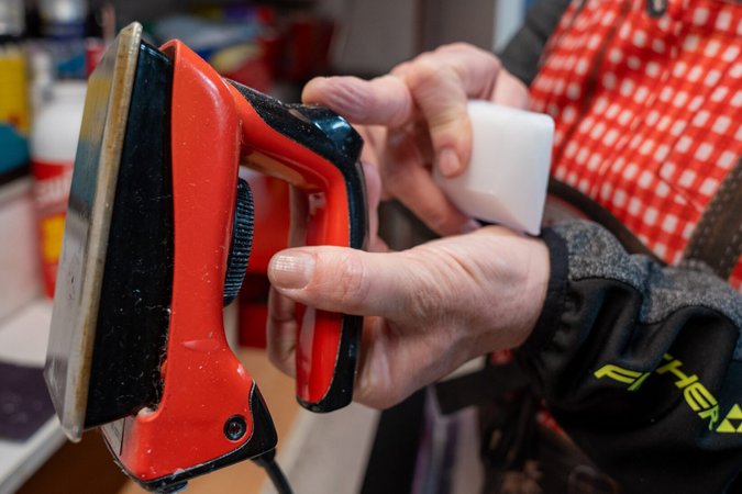 Person hält ein Rot- und Schwarze Bügeleisen und ein weißes Werkzeug in der Hand