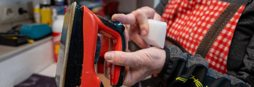 Person hält ein Rot- und Schwarze Bügeleisen und ein weißes Werkzeug in der Hand