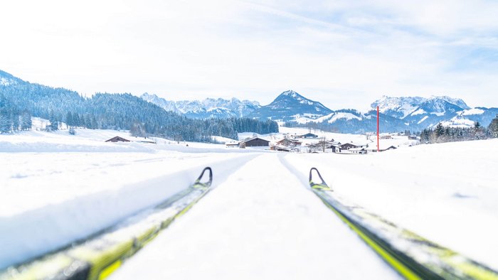 Kaiserwinkl: eine Langlaufregion der Superlative © Tourismusverband Kaiserwinkl Langlaufskier auf schneebedeckter Loipe mit Bergen im Hintergrund