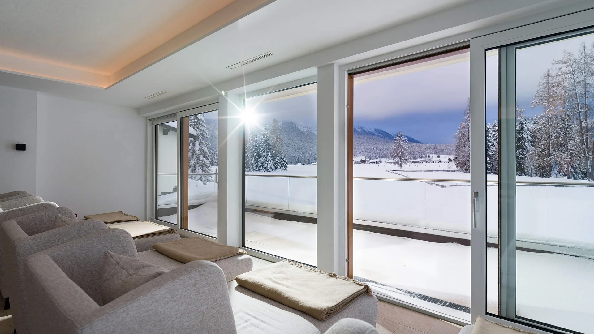 Cozy lounge chairs with blankets by large windows overlooking snowy landscape