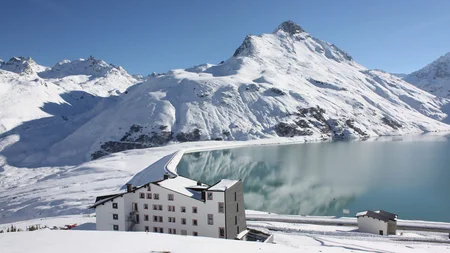 Schneebedeckte Berge und See mit weißem Gebäude im Vordergrund