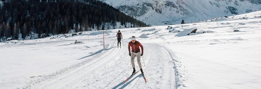 Langlauf in verschneiter Berglandschaft bei sonnigem Wetter