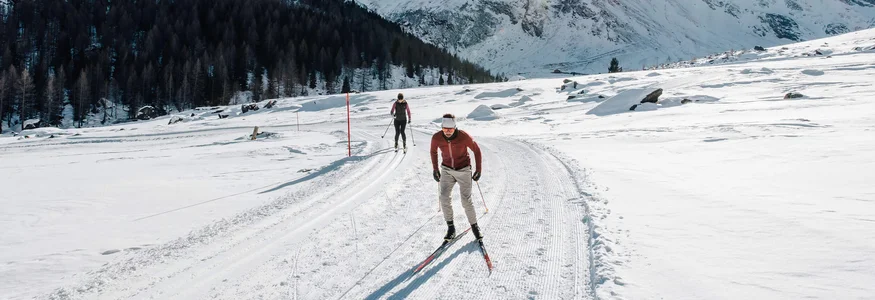 Langlauf in verschneiter Berglandschaft bei sonnigem Wetter