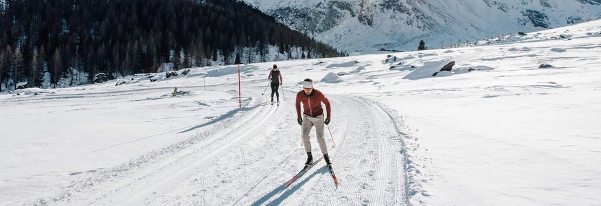 Langlauf in verschneiter Berglandschaft bei sonnigem Wetter