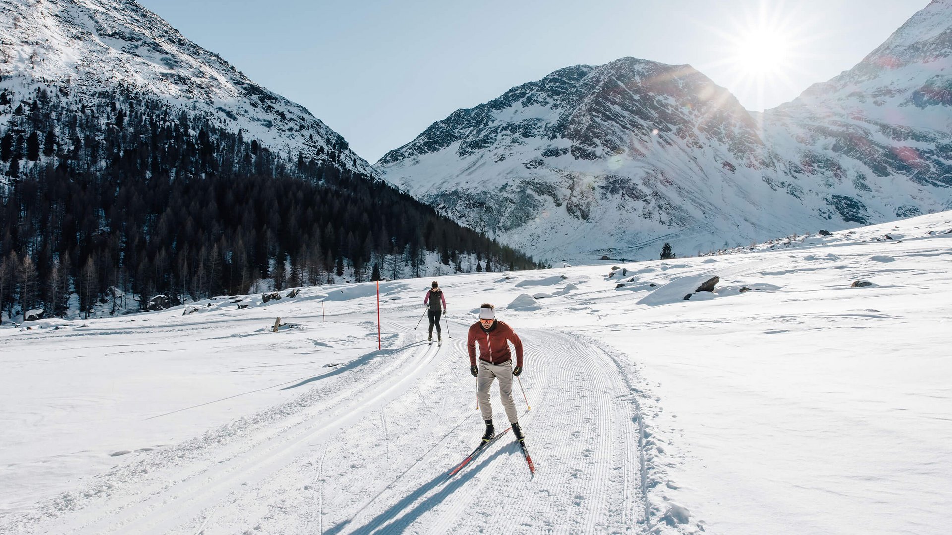 Langlauf in verschneiter Berglandschaft bei sonnigem Wetter