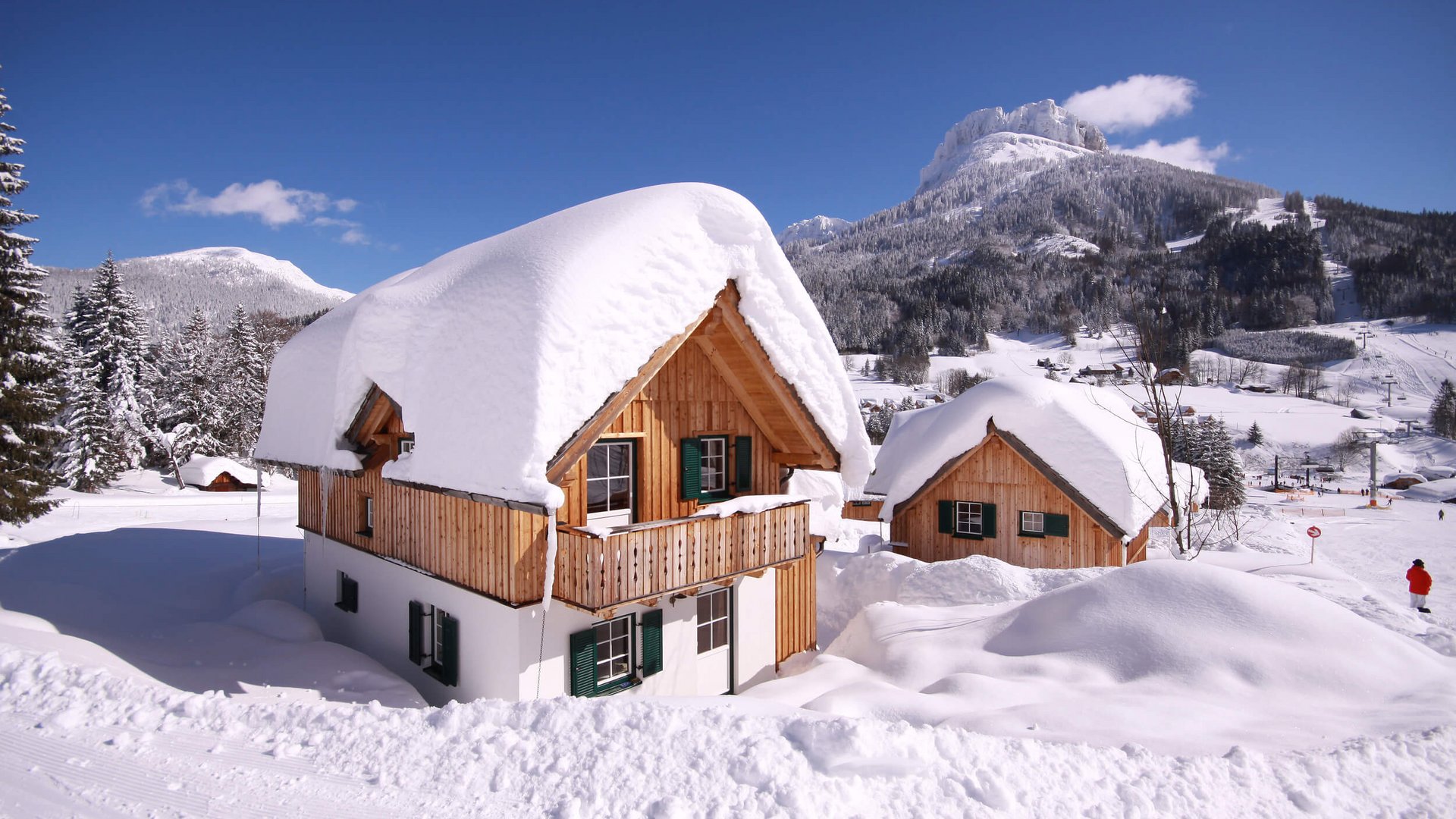Wooden houses covered in thick snow in a mountain winter landscape
