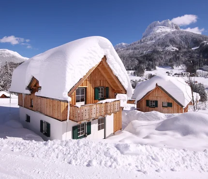 Wooden houses covered in thick snow in a mountain winter landscape