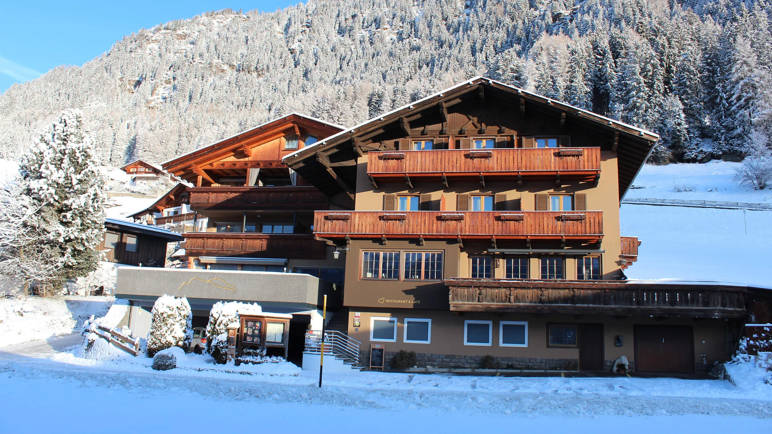 Holzhaus im Schnee vor verschneiten Bergen und klarem blauem Himmel