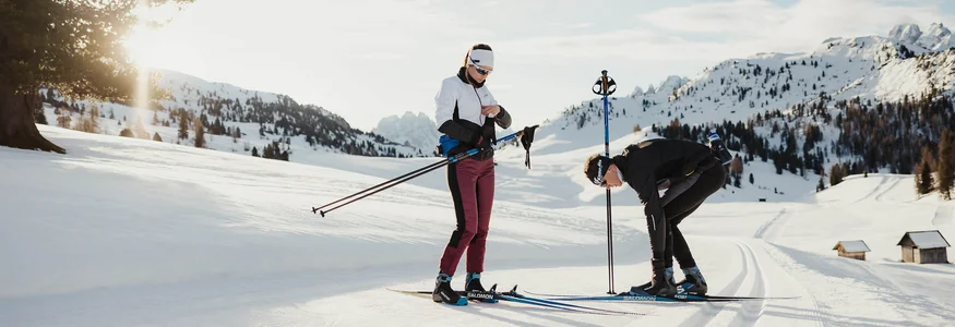 Zwei Menschen bereiten sich auf Langlauf in verschneiter Berglandschaft vor