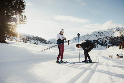 Zwei Menschen bereiten sich auf Langlauf in verschneiter Berglandschaft vor