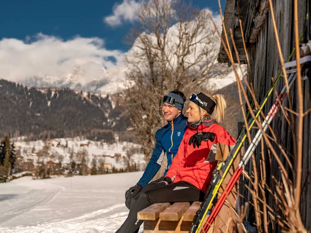 Schneesicher langlaufen: Wo Snowfarming in Österreich frühen Saisonstart möglich macht
© TVB Schladming Dachstein - Christine Höflehner Zwei Personen in Winterkleidung sitzen auf einer Bank mit Skistöcken neben einem Holzhaus