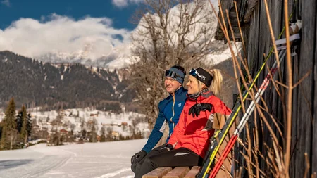 Schneesicher langlaufen: Wo Snowfarming in Österreich frühen Saisonstart möglich macht
© TVB Schladming Dachstein - Christine Höflehner Zwei Personen in Winterkleidung sitzen auf einer Bank mit Skistöcken neben einem Holzhaus