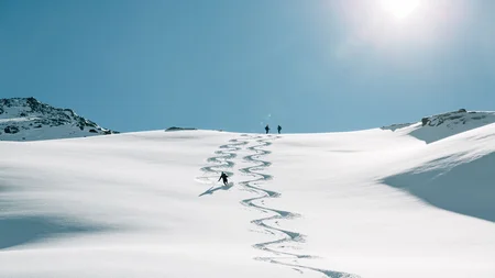 Skier carving tracks in fresh snow on sunny mountain slope