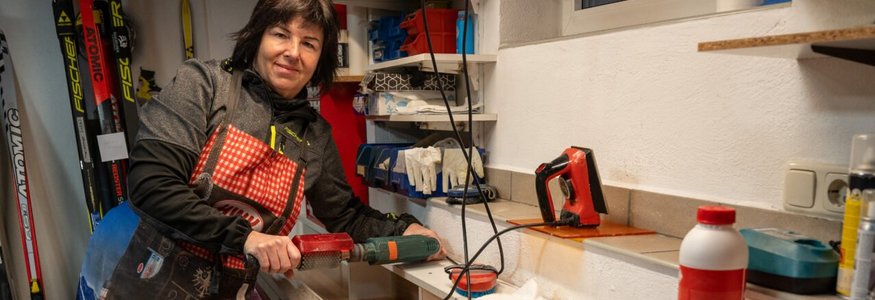 Frau bearbeitet Ski mit elektrischem Werkzeug in Werkstatt
