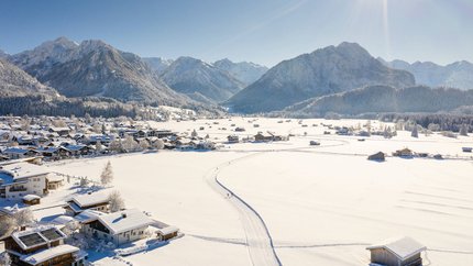 Snow-covered village and mountains under clear sky with bright sun