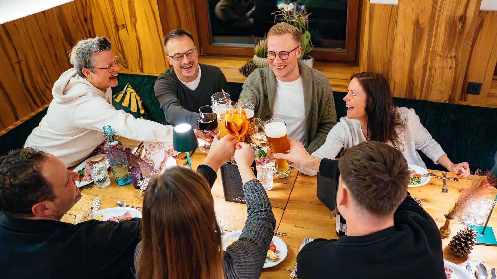 Friends clinking glasses together around a table while having a meal