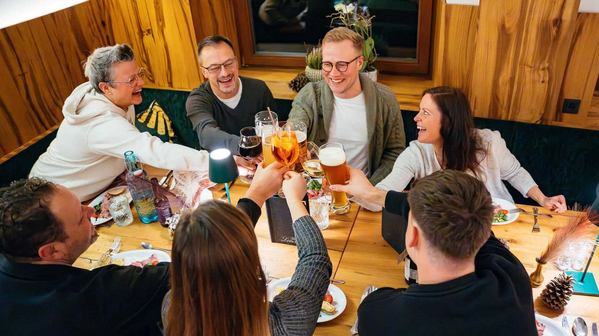 Freunde stoßen in gemütlicher Runde bei einem Essen mit Getränken an
