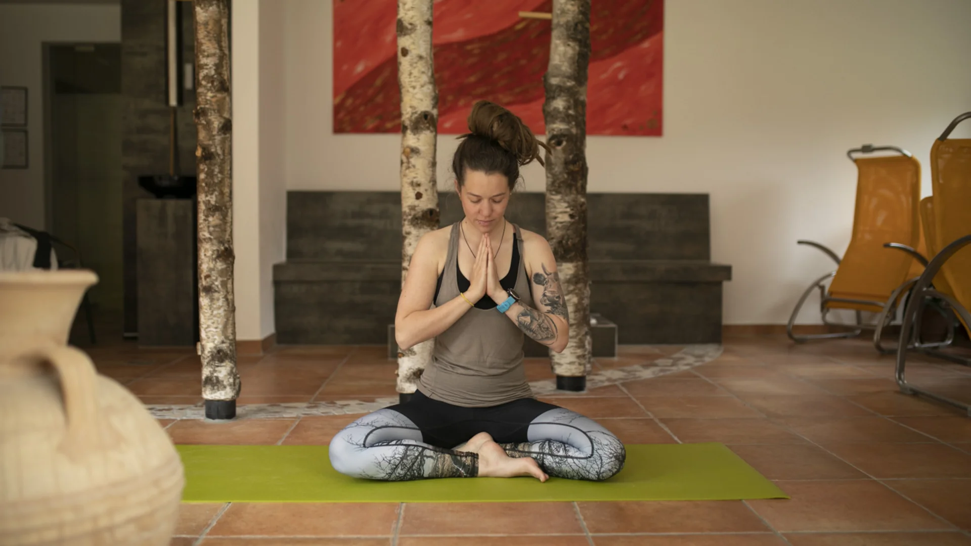 Frau meditiert im Lotussitz auf Yogamatte in Innenraum