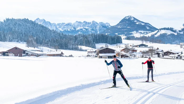 Zwei Langläufer auf verschneiter Loipe in alpiner Winterlandschaft