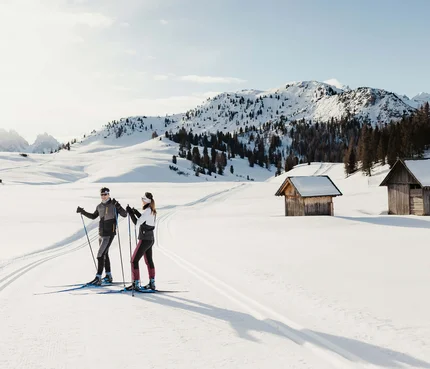 Dolomitenregion Drei Zinnen © Alex Moling Zwei Skifahrer auf gespurter Loipe in verschneiter Berglandschaft mit Hütten