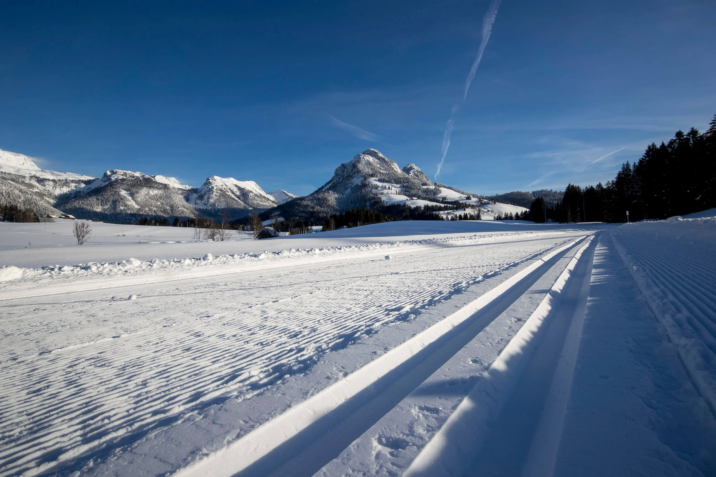 Groomed cross-country ski trail with snow-covered mountains in the background