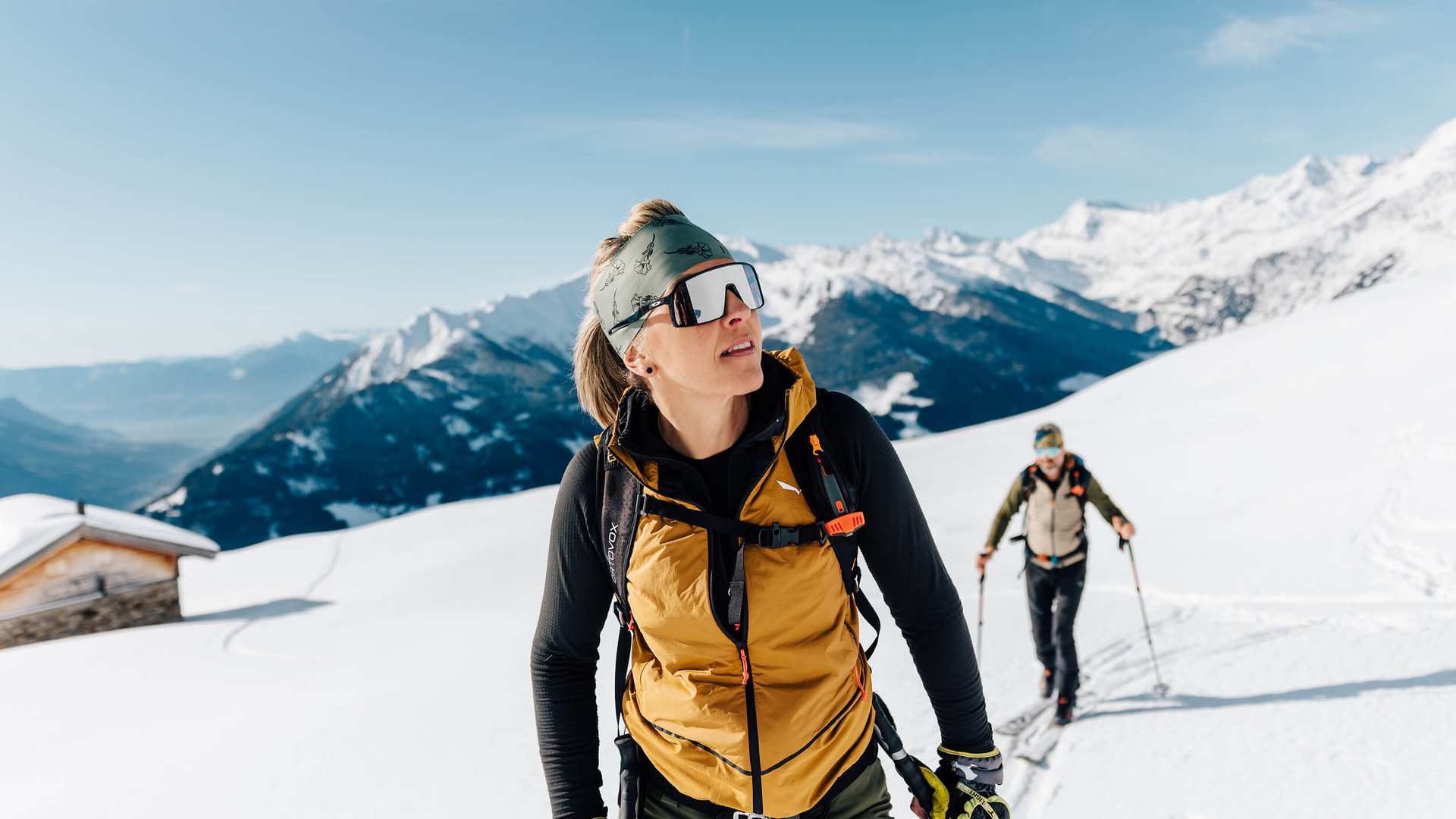 Frauen wandern mit Skiern auf verschneitem Berg bei klarem Himmel