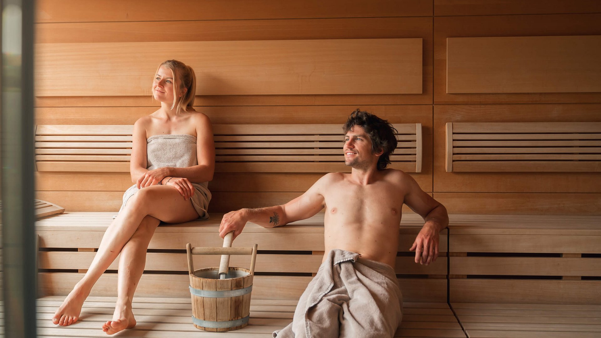 Man and woman relaxing together in a wooden sauna