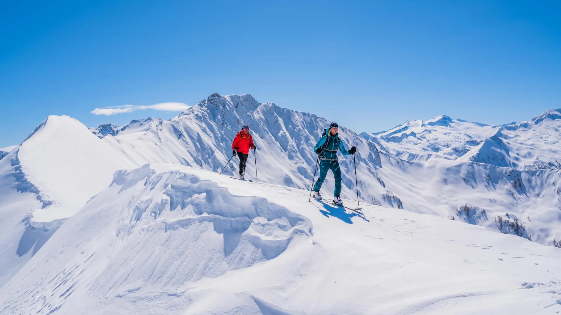 Zwei Skitourengeher wandern auf schneebedecktem Berg im sonnigen Winter