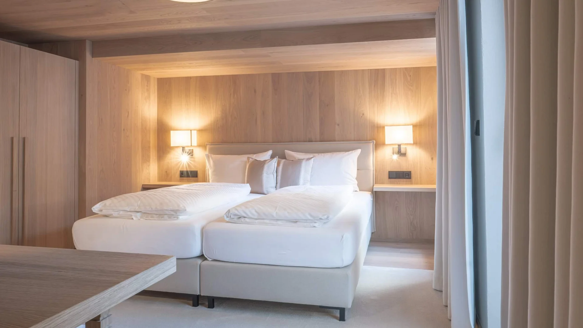 Genuss- und Aktivhotel Sonnenburg **** © Elisa Moosbrugger Helles Hotelzimmer mit Doppelbett, Holzverkleidung und zwei Nachttischlampen