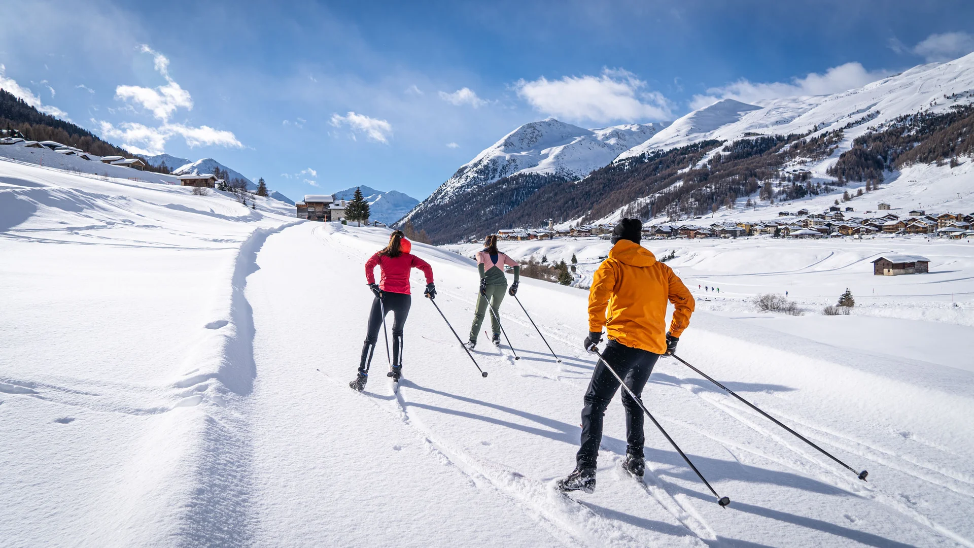Three people cross-country skiing in snowy mountain landscape