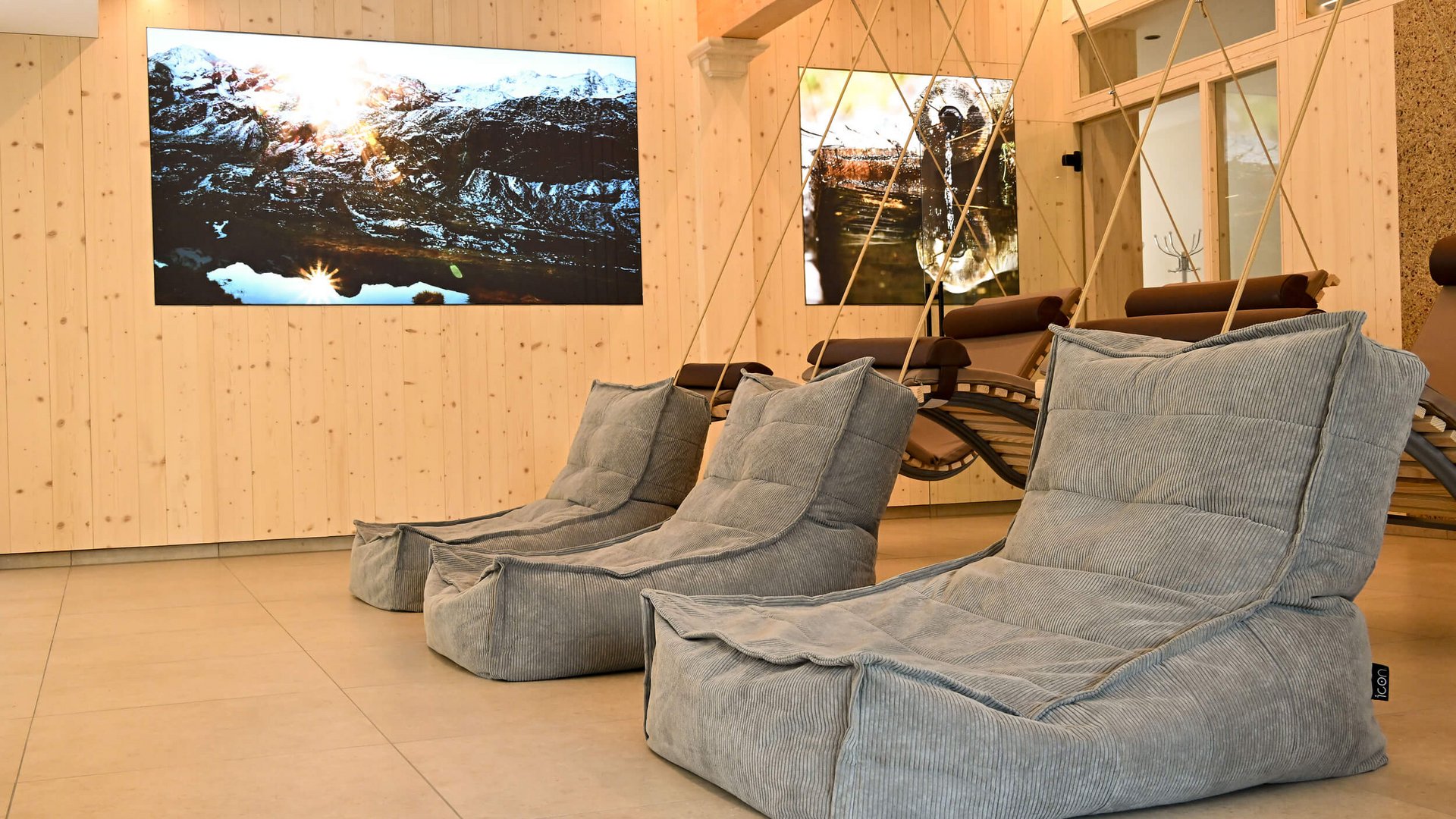 Moderne Lounge mit grauen Sesseln und Naturfotos an hellen Holzwänden
