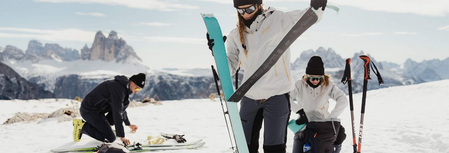 Personen bereiten Ski und Ausrüstung auf schneebedecktem Berg vor