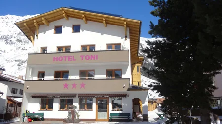 Außenansicht von Hotel Toni mit Bergen und Schnee im Hintergrund