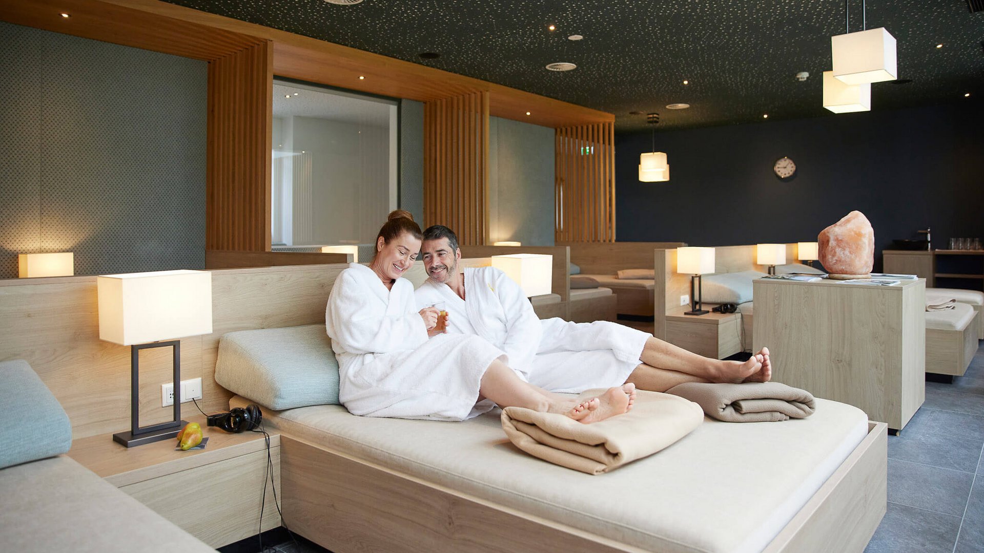 Couple relaxing in robes on lounge bed in spa area