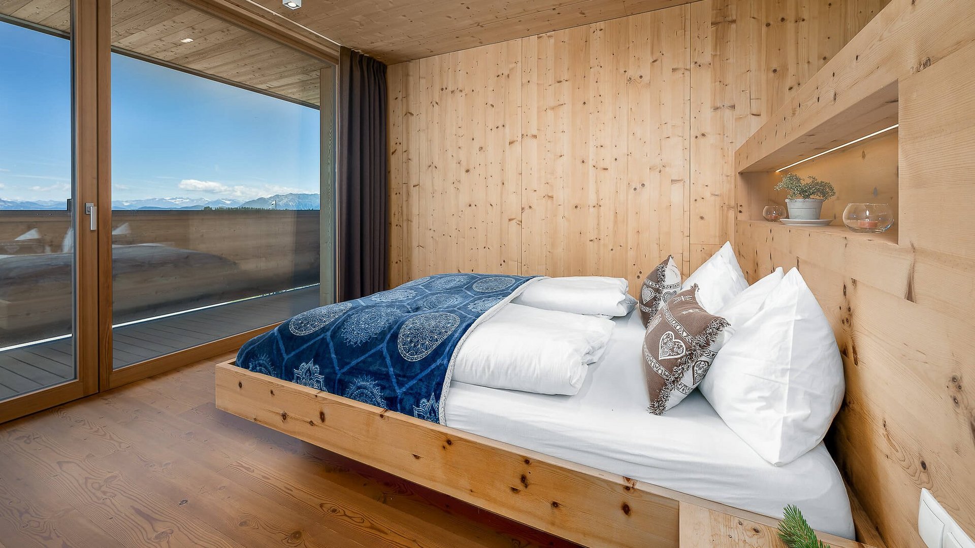 Holzschlafzimmer mit großem Fenster und Bergblick