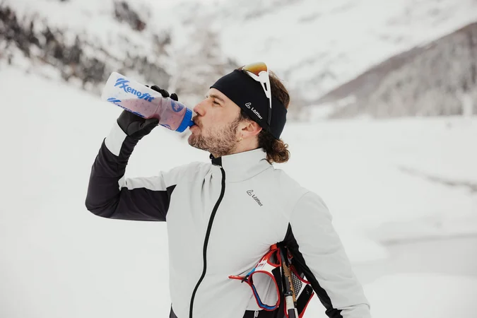 Langlauf Urlaub © Alex Moling Mann in Winterkleidung trinkt aus einer Trinkflasche im verschneiten Gebirge