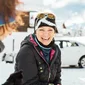 Smiling woman in winter clothing standing in the snow beside another person