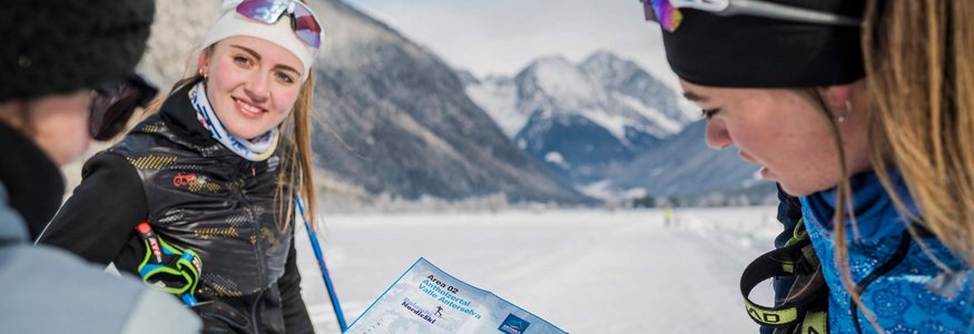 Gruppe von Langläufern mit Karte vor verschneiten Bergen
