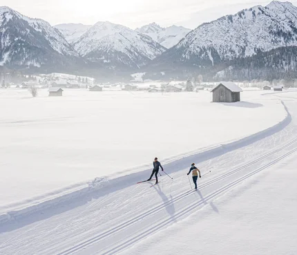 Oberstdorf © Frithjof Kjer Zwei Skifahrer auf einer Loipe vor verschneiten Bergen bei Sonnenschein