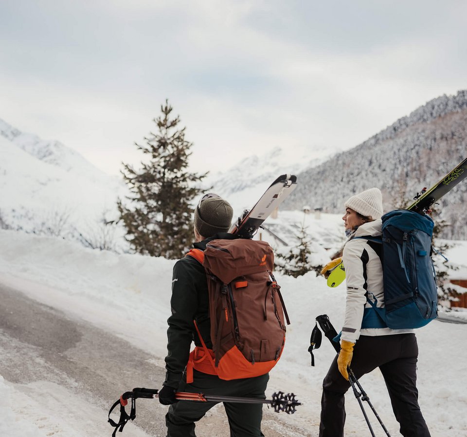 HOW TO SKITOUR © Alex Moling Zwei Skifahrer mit Rucksäcken und Skiern gehen einen schneebedeckten Bergweg hinauf